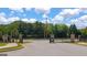 Gated entrance to a community with well-maintained landscaping and a paved street with lush trees in the background at 1724 Goodwin Dr # 74, Hampton, GA 30228
