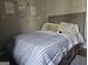 Bedroom featuring a queen bed with blue and white patterned quilt, neutral walls, and plush pillows at 6558 Eastbriar Dr, Lithonia, GA 30058
