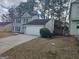 A two-story, gray house with a two-car garage, green lawn, and privacy bushes at 6558 Eastbriar Dr, Lithonia, GA 30058