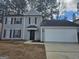 Two-story home featuring gray siding, black shutters, a white garage door, and a well-manicured front yard at 6558 Eastbriar Dr, Lithonia, GA 30058