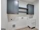Well-lit laundry room with gray cabinets, open shelving, white sink and wood-look tile flooring at 859 N Bay Overlook, Villa Rica, GA 30180
