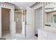 Bathroom with a glass enclosed shower, white cabinets, wallpaper, mirror, and an open closet at 123 Stratmore Pl, Stockbridge, GA 30281