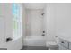 Bathroom featuring sleek white tiles, dark fixtures, and a combined tub and shower at 930 Laurel Brooke Ave, Peachtree City, GA 30269