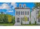 Beautiful three-story home with white brick, black shutters, a manicured lawn, and professional landscaping at 930 Laurel Brooke Ave, Peachtree City, GA 30269