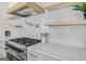 Updated kitchen features subway tile backsplash, stainless steel range hood, pot filler, and wooden shelving at 930 Laurel Brooke Ave, Peachtree City, GA 30269