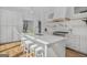 Open-concept kitchen with a large marble island, stainless steel appliances, and floating shelves at 930 Laurel Brooke Ave, Peachtree City, GA 30269