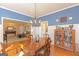Formal dining room with blue walls, hardwood floors, wainscotting, and chandelier lighting at 245 Longshore Way, Fayetteville, GA 30215