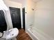 Bright bathroom features a tub with shower and pedestal sink with modern fixtures at 1209 Topaz Ln, Villa Rica, GA 30180