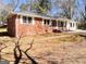 Red brick home with white trim and a well-manicured lawn, set against a backdrop of mature trees at 1209 Topaz Ln, Villa Rica, GA 30180