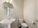 Modern powder room features a pedestal sink, round mirror, and neutral paint at 536 Caledon Way, Hampton, GA 30228