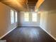 Spacious basement area with dark hardwood floors, three windows, and exposed ceiling at 6740 Davidson Ct, Lithonia, GA 30058