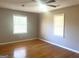 A bright bedroom featuring two windows, hardwood floors, and a ceiling fan at 6740 Davidson Ct, Lithonia, GA 30058