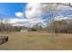 Large backyard with a distant outbuilding under a cloudy blue sky at 240 Sandy Lake Cir, Fayetteville, GA 30214