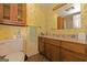 A quaint bathroom featuring a wooden vanity, marble countertops, and warm floral wallpaper at 240 Sandy Lake Cir, Fayetteville, GA 30214