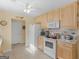 Well-lit kitchen with white appliances, light wood cabinets, and tile flooring at 509 Carleton Pl, Locust Grove, GA 30248