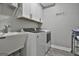 Well-lit laundry room with modern washer and dryer, sink, and storage cabinets at 285 Hogan Coweta Rd, Hogansville, GA 30230