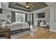 This main bedroom has light wood floors, a tray ceiling with ceiling fan, a large window and a TV at 285 Hogan Coweta Rd, Hogansville, GA 30230