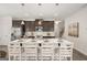 Kitchen island with white countertop, dark cabinets, seating for four, and pendant lighting at 10471 Trellis Lane (Lot 25), Hampton, GA 30228