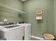 This laundry room features a washer and dryer, a metal shelf and a decorative laundry room sign at 10471 Trellis Lane (Lot 25), Hampton, GA 30228