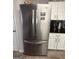 Modern stainless steel refrigerator complementing the kitchen's white cabinets and black backsplash at 1631 Royal Ives Dr, Lawrenceville, GA 30045