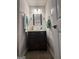 Updated powder room with a single dark wood vanity, framed mirror, modern fixtures and tile flooring at 1631 Royal Ives Dr, Lawrenceville, GA 30045