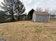 Spacious backyard featuring a utility shed, grass, and a backdrop of trees and neighboring homes at 1631 Royal Ives Dr, Lawrenceville, GA 30045