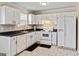 Well-lit kitchen with white cabinetry, black countertops, and modern appliances at 261 Whistle Way, Locust Grove, GA 30248