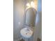 Charming powder room featuring a pedestal sink, arched mirror, and updated lighting at 5790 Ridge Stone Way, Cumming, GA 30041