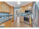 Well-lit kitchen featuring wood cabinetry, stainless steel appliances, granite countertops, and tile flooring at 130 Kingsbrooke Cir, Palmetto, GA 30268