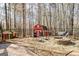 Charming backyard featuring a stone fire pit, seating area, and colorful sheds surrounded by mature trees at 233 Spear Rd, Fayetteville, GA 30215