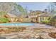 Backyard view of a large custom home featuring a pool and brick patio with manicured landscaping at 233 Spear Rd, Fayetteville, GA 30215