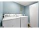 Well-lit laundry room with a white washer and dryer set ready for use and a light blue wall at 623 Swan Lake Rd, Stockbridge, GA 30281