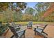 Charming brick patio featuring comfortable Adirondack seating in a serene, wooded backyard setting at 375 Darren Dr, Fayetteville, GA 30215