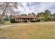 Exterior front view of single-story wood home with a well-manicured lawn, trees, and mature landscaping at 5687 Highway 212 N, Covington, GA 30016