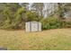 Metal shed located on a spacious grassy lot, surrounded by dense trees and greenery at 5687 Highway 212 N, Covington, GA 30016