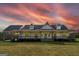 Charming farmhouse with an expansive front porch, pristine white siding, and a lush green lawn at sunset at 271 Trestle Rd, Locust Grove, GA 30248