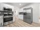 Modern kitchen with stainless steel appliances, white cabinets, gray backsplash, and wood flooring for a sleek design at 2391 Wellborn Hills Ct, Lithonia, GA 30058