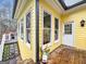 Corner view of yellow house featuring windows, a white door, wooden deck, stairs, and an outdoor light at 160 Allie Dr, Mcdonough, GA 30252