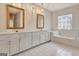 Bathroom featuring double vanity, white cabinetry, white tile floors, bathtub with decorative window above at 40 High St, Sharpsburg, GA 30277