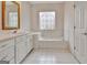 Bathroom featuring bathtub with decorative window, double vanity, white cabinetry, and white tile floors at 40 High St, Sharpsburg, GA 30277