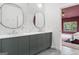 Modern bathroom featuring double sinks, sleek gray vanity, and stylish round mirrors, next to the main bedroom entry at 612 Champions Dr, Mcdonough, GA 30253