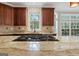 Granite countertop island with cooktop, dark wood cabinets and backsplash at 612 Champions Dr, Mcdonough, GA 30253