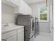 Bright laundry room with stainless steel washer and dryer plus white cabinets and tiled floors at 612 Champions Dr, Mcdonough, GA 30253