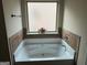Bathroom featuring a large tub with tile accents, complemented by a frosted window at 7522 Springbox Dr, Fairburn, GA 30213
