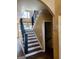 Elegant staircase featuring dark wood railing and white risers, with an arched doorway and light-filled landing at 245 Ashley Forest Dr, Fayetteville, GA 30214