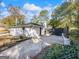 Rear exterior view of house with fenced parking, white painted brick, and mature trees at 3044 Sunset Ln, East Point, GA 30344