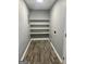 Neutral laundry room offers wooden floors and four white shelves for convenient storage at 23 Hampton Locust Grove Rd, Hampton, GA 30228