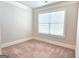 An empty bedroom with neutral walls, carpeting, and bright window is move-in ready at 207 Birchwood Dr, Loganville, GA 30052
