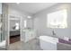 Modern bathroom featuring a soaking tub, elegant vanity, and a view to the bedroom with hardwood floors at 1408 Hemphill Rd, Stockbridge, GA 30281