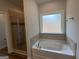 Luxurious bathroom showcasing a glass-enclosed shower and a separate soaking tub with tile surround and a window at 5311 Tuscany Dr # 98 Plapprox Sqft, Douglasville, GA 30135